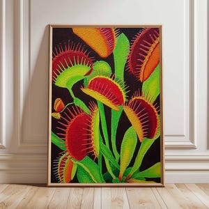 Op de afbeelding: Een ingelijste print met een levendige weergave van Venus vliegenvallen. Het kunstwerk toont de vleesetende planten met heldere rode, gele en groene tinten tegen een donkere achtergrond. De afbeelding is ingelijst in een lichtbruine houten lijst.