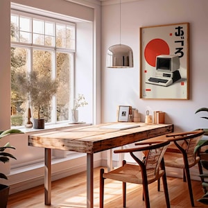 Puede incluir: Una habitaci&oacute;n con un escritorio de madera y dos sillas. Un p&oacute;ster enmarcado en la pared presenta un dise&ntilde;o de ordenador vintage con texto japon&eacute;s y un c&iacute;rculo rojo. Una gran ventana ofrece una vista de &aacute;rboles y luz natural.