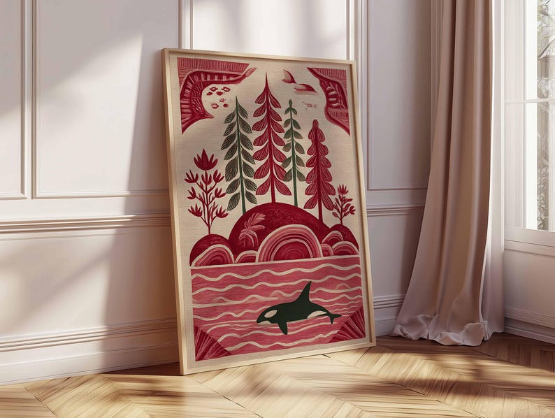 May include: Framed art print featuring a stylized landscape with red and green trees, rolling hills, and a body of water. A black and white orca swims in the water. The artwork is in a wooden frame and leans against a white wall and wooden floor.