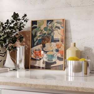 May include: A framed painting of a still life with a potted plant, five teacups, and saucers on a table. The teacups are in various colors, including red, blue, and white. The painting is set against a white wall.