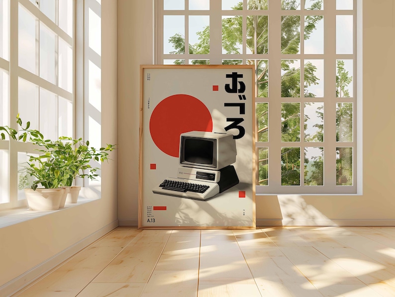 Puede incluir: Un p&oacute;ster enmarcado con un dise&ntilde;o de ordenador retro, un c&iacute;rculo rojo y texto japon&eacute;s. El ordenador es blanco y negro, con teclado y monitor. El p&oacute;ster est&aacute; apoyado en una pared cerca de una ventana.