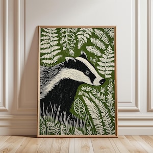 Op de afbeelding: Een ingelijste kunstdruk met een zwart-wit illustratie van een das tegen een groene achtergrond met witte varenachtige bladeren. De das is in profiel afgebeeld, in gedetailleerde linoleumsnede stijl.