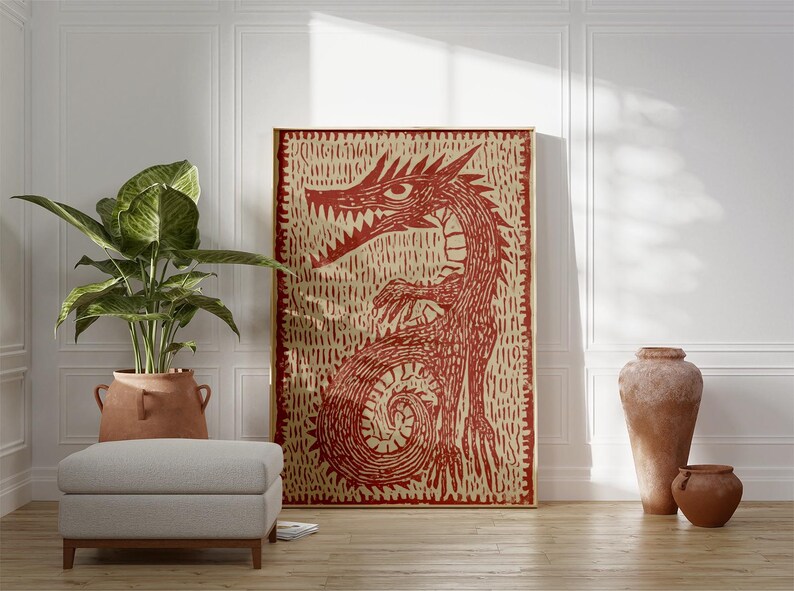 May include: A large framed artwork featuring a red dragon illustration on a beige background. The dragon is depicted with sharp teeth and claws. The artwork is displayed in a room with a plant, ottoman, and decorative vases.