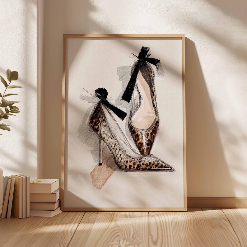 Op de afbeelding: Een ingelijste kunstafdruk van twee pumps. De schoenen hebben een luipaardprint, spitse neuzen en zwarte strikken. Het kunstwerk is gepresenteerd in een licht houten frame, geschikt voor een slaapkamer of kleedkamer.