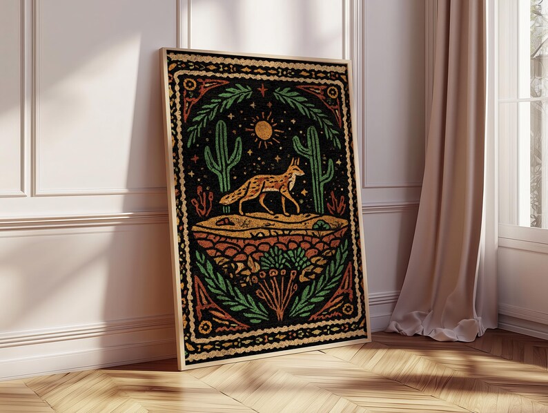 May include: A framed art print featuring a desert scene with a fox, cacti, and sun. The artwork has a black background with orange, green, and yellow accents. The print is displayed on a wooden floor, leaning against a white wall.