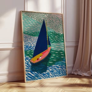 May include: A framed art print depicting a sailboat on water. The boat has a blue sail and a yellow and pink hull. The water is shown in shades of blue and green, and the sky is a light green colour.