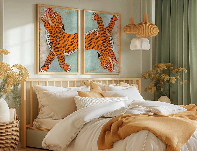 May include: Two framed prints of orange tigers on a blue background, hanging above a wooden bed frame with white bedding and a mustard yellow throw blanket.