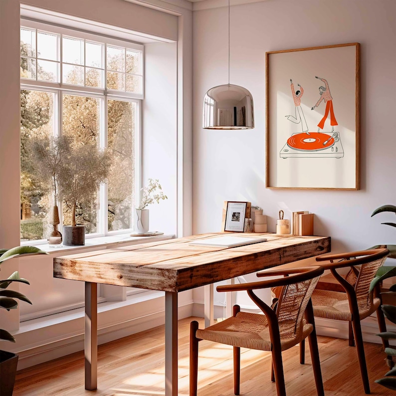 Puede incluir: Una habitaci&oacute;n luminosa con un escritorio de madera y dos sillas. Una impresi&oacute;n enmarcada de figuras bailando sobre un tocadiscos cuelga de la pared. Una gran ventana ofrece vistas a los &aacute;rboles. Una l&aacute;mpara colgante plateada cuelga sobre el escritorio.