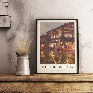 May include: A framed print of a painting by Hiroshi Yoshida titled "Evening After Rain, 1926". The painting depicts a street scene in Japan with buildings, people, and reflections in the water.