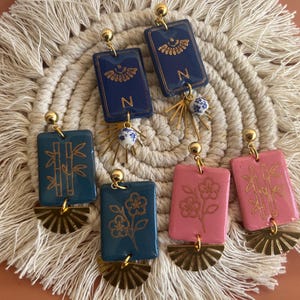 May include: A set of three ceramic mugs with a speckled, matte finish. The mugs are in shades of cream, light gray, and dark gray. Each mug has a simple, minimalist design, perfect for coffee or tea.