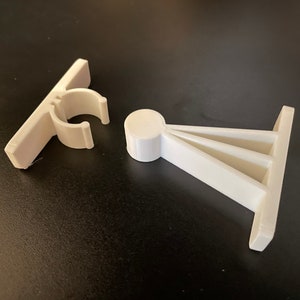 May include: Two white plastic door stops. One is a simple, flat stop with a clip. The other is a triangular stop with a rounded base.