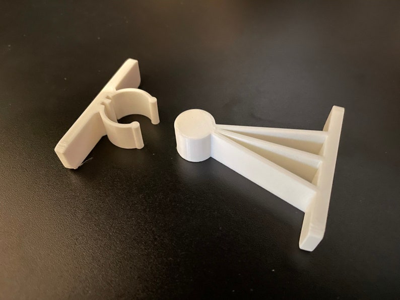 May include: Two white plastic door stops. One is a simple, flat stop with a clip. The other is a triangular stop with a rounded base.