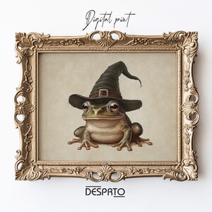 May include: Digital print of a frog wearing a black witch hat, in a gold ornate frame. The frog is green and brown with large eyes. The frame has detailed patterns. The text "Digital print" is at the top, and "DESPRTO" is at the bottom.