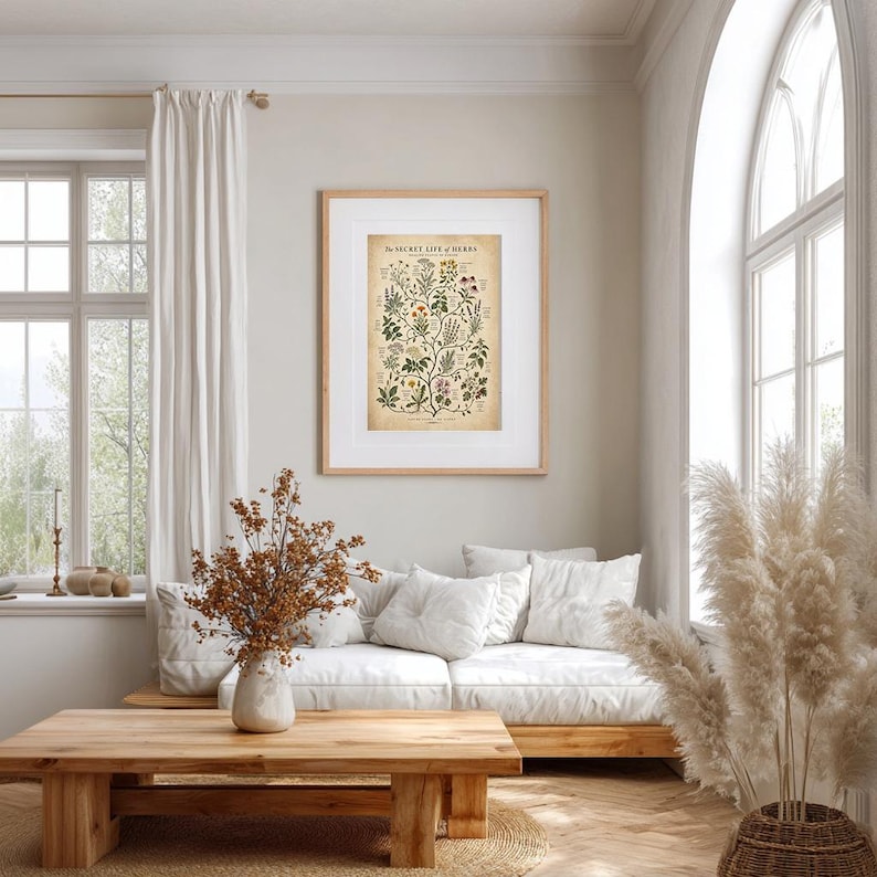 May include: A framed botanical wall art print titled The Secret Life of Herbs, featuring detailed illustrations of various plants with text labels, displayed in a light wood frame with a white mat on a neutral wall above a white sofa.