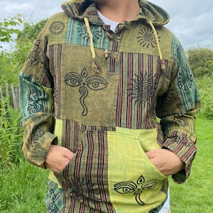 Puede incluir: Una camisa con capucha de patrón verde, marrón y amarillo con capucha con cordón y cierre de botón. La camisa tiene un bolsillo en la parte delantera y presenta una variedad de símbolos y diseños.