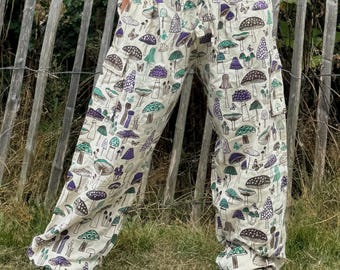 May include: White trousers with a mushroom print. The trousers have an elastic waistband and a drawstring. The mushrooms are in shades of purple, green, and brown.