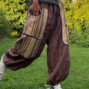 Puede incluir: Pantalones harén marrones con detalles de bolsillos estampados. Los pantalones tienen un corte holgado con tobillo recogido y presentan un diseño a rayas en los bolsillos. Los pantalones están hechos de un material suave y son adecuados para uso casual.