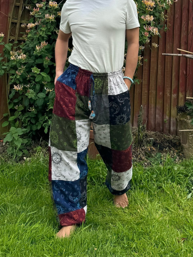 Puede incluir: Pantalones holgados de patchwork con un estampado celestial de soles, lunas y estrellas en varios colores, incluyendo azul oscuro, rojo intenso, verde oliva y blanco. Los pantalones tienen una cintura el&aacute;stica con cord&oacute;n y bolsillos laterales.