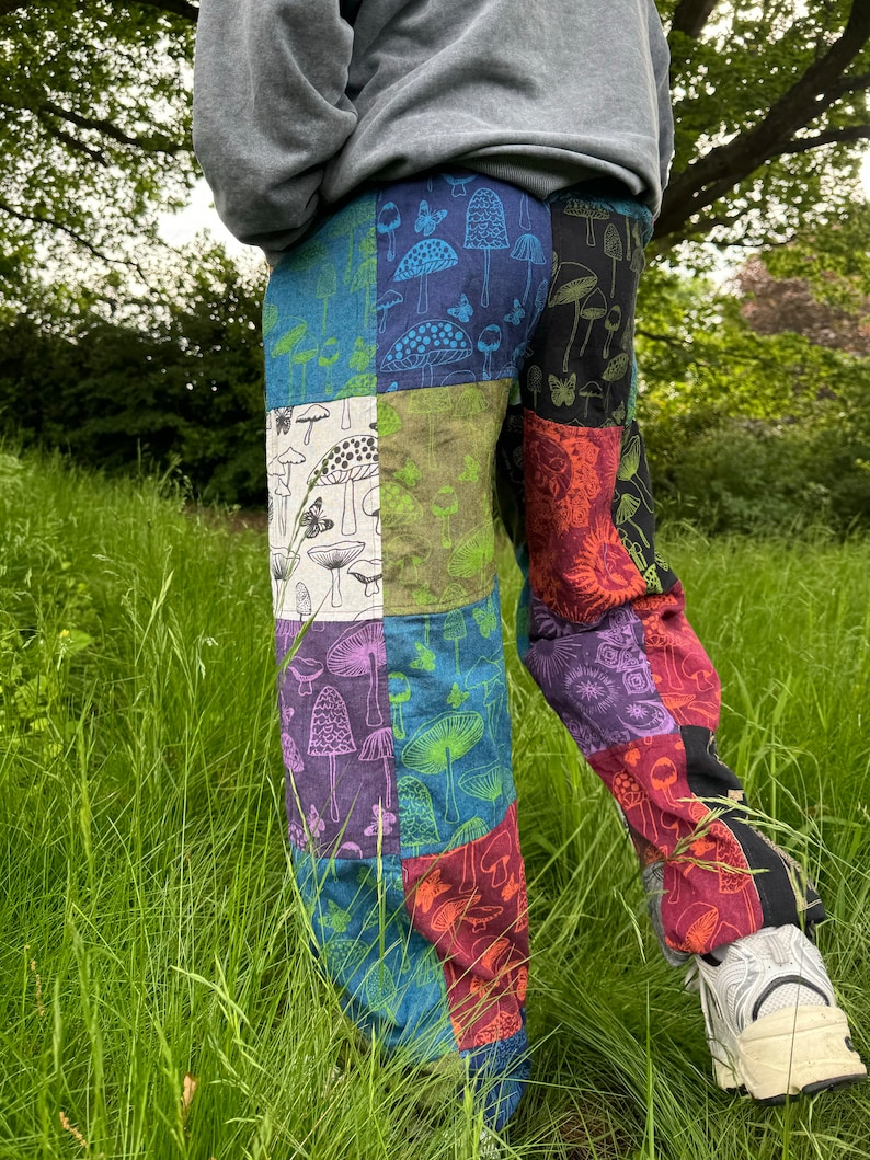Puede incluir: Pantalones de patchwork con un dise&ntilde;o multicolor que presenta varios patrones de setas y mariposas. Los paneles de tela incluyen tonos de azul, verde, blanco, morado, rojo y negro, cosidos para formar una prenda de pantal&oacute;n largo.