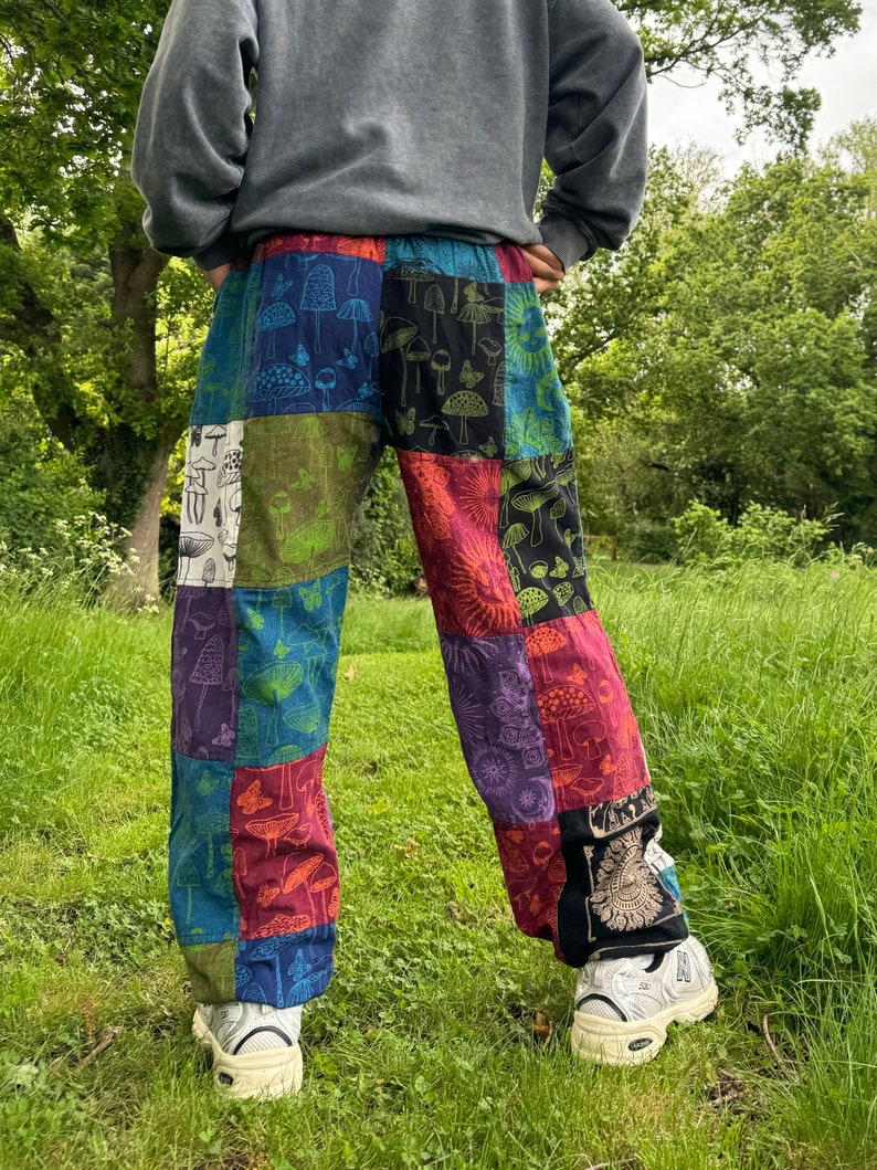 Puede incluir: Pantalones de patchwork con un dise&ntilde;o multicolor y varios estampados de setas y mariposas. Los pantalones est&aacute;n confeccionados con paneles de tela rectangulares en tonos azul, verde, rojo, morado y negro, con un patr&oacute;n repetitivo.