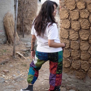 Puede incluir: Una camiseta blanca de manga corta combinada con pantalones de patchwork holgados con un estampado multicolor de setas y soles. Los pantalones tienen pu&ntilde;os el&aacute;sticos en los tobillos y se llevan con zapatillas altas de color negro y blanco.