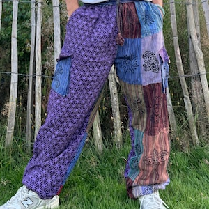 May include: Purple, blue, and brown patchwork pants with a geometric pattern and embroidered details. The pants have a drawstring waist and cargo pockets.