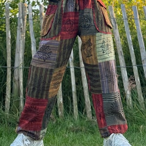 Könnte beinhalten: Patchwork-Hose mit einem mehrfarbigen Design in Braun, Rot, Grün und Lila. Die Hose hat einen Kordelzugbund und Seitentaschen.