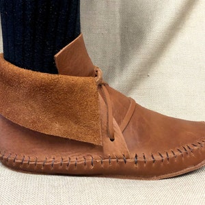 Peut inclure: Bottines en cuir marron avec un revers en daim et une couture d&eacute;corative autour de la semelle.