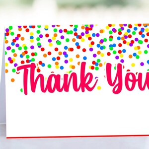 May include: A white thank you card with a red border. The card is decorated with a colorful confetti pattern. The text "Thank You" is written in pink.