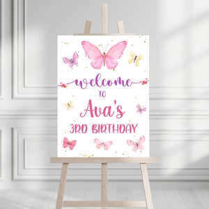 May include: Welcome to Ava's 3rd Birthday sign with pink butterflies and gold glitter on a white background.