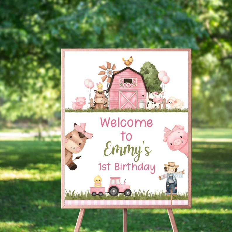 May include: Welcome to Emmy's 1st Birthday sign with a pink barn, farm animals, and a tractor. The sign is on a wooden easel.