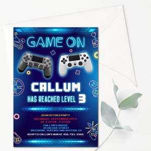 May include: A blue and neon-colored invitation for a video game themed party. The invitation says "Game On" and "Callum has reached level 3". It also includes a date, time, and location for the party.
