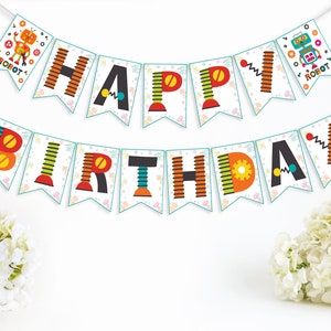 Peut inclure: Une bannière d'anniversaire colorée avec des lettres et des illustrations sur le thème des robots. La bannière est enfilée sur une ficelle blanche et a un fond blanc.