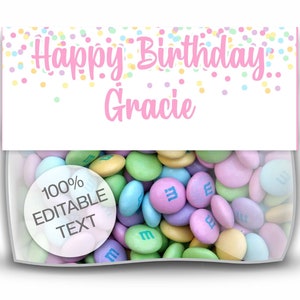Op de afbeelding: Een doorzichtige cellofaan zak gevuld met pastelkleurige snoepjes. De zak heeft een wit label met "Happy Birthday Gracie" in roze letters, met kleurrijke confetti. Een ronde sticker zegt "100% Bewerkbare tekst".