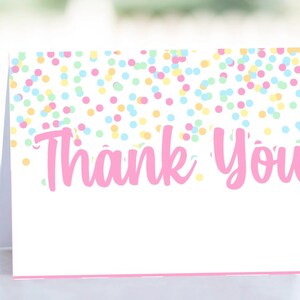 Op de afbeelding: Een witte gevouwen kaart met een roze rand en de woorden "Thank You" in roze script. De bovenkant van de kaart is versierd met kleurrijke confetti stippen in roze, geel, blauw en groen.