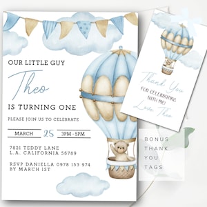 May include: A blue and white hot air balloon with a teddy bear in the basket. The balloon is surrounded by clouds and a banner with flags. The text "Our Little Guy Theo Is Turning One" is at the top of the invitation. The invitation also includes the date, time, and location of the party. The text "Thank You For Celebrating With Me Love Theo" is on a separate card with a blue and white hot air balloon with a teddy bear in the basket.