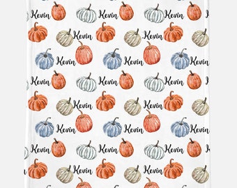 Puede incluir: Un fondo blanco con un patrón repetido de calabazas azules, naranjas y blancas. Las calabazas están decoradas con el nombre "Kevin" en escritura cursiva negra.