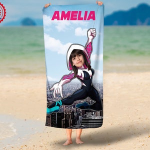 May include: A white beach towel with a colorful cartoon image of a superhero. The superhero is wearing a pink and white suit and has a girl's face in the head. The towel has the name "AMELIA" printed at the top.