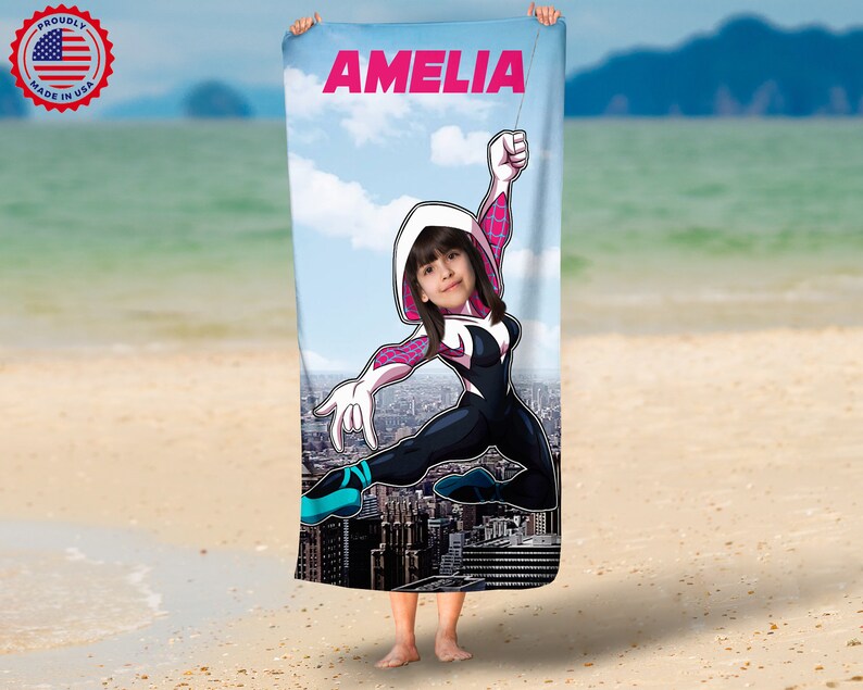 May include: A white beach towel with a colorful cartoon image of a superhero. The superhero is wearing a pink and white suit and has a girl's face in the head. The towel has the name "AMELIA" printed at the top.