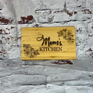May include: A wooden cutting board with the text "Mom's Kitchen" and a floral design.
