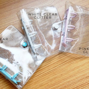 以下が含まれることがあります： キラキラ光る透明なプラスチックバインダーが3つ。バインダーには、「ホワイトクリアグリッター」、「ブルークリアグリッター」、「ピンククリアグリッター」とラベルが貼られています。