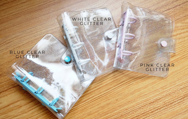 以下が含まれることがあります： キラキラ光る透明なプラスチックバインダーが3つ。バインダーには、「ホワイトクリアグリッター」、「ブルークリアグリッター」、「ピンククリアグリッター」とラベルが貼られています。