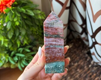 May include: A red, green, and white striped crystal point. The crystal is polished and has a smooth, shiny surface.