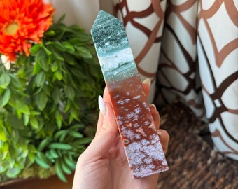 May include: A green, white, and red agate crystal point. The crystal is polished and has a smooth, shiny surface. The point is about 5 inches long.