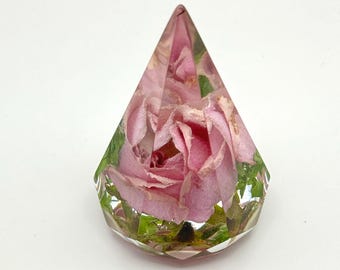Op de afbeelding: Een heldere, facetgeslepen hars papgewigt met een roze roos en groen blad. De roos is het middelpunt, met zijn bloemblaadjes zichtbaar door de transparante hars. Het papgewigt heeft een diamantachtige vorm.