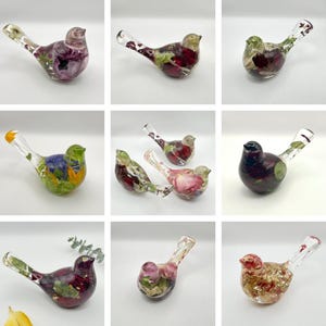 Op de afbeelding: Een verzameling decoratieve glazen vogelbeeldjes. Elke vogel is gevuld met kleurrijke gedroogde bloemen en bladeren, met een verscheidenheid aan tinten, waaronder rood, paars, groen en geel. De vogels hebben heldere glazen snavels en staarten.