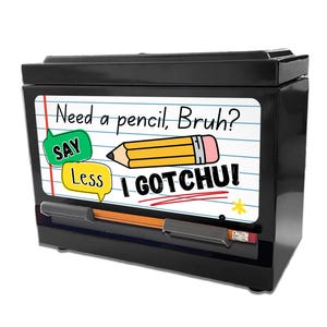 May include: Black pencil dispenser with a white notepad design on the front. The notepad has the text "Need a pencil, Bruh?" and "I GOTCHU!" with a cartoon pencil graphic. A pencil is visible in the dispenser.