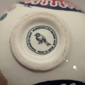 May include: The bottom of a white ceramic bowl with a black and white bird illustration and the text "Microwave & Dishwasher Safe. Made in China.  Parsol in China."