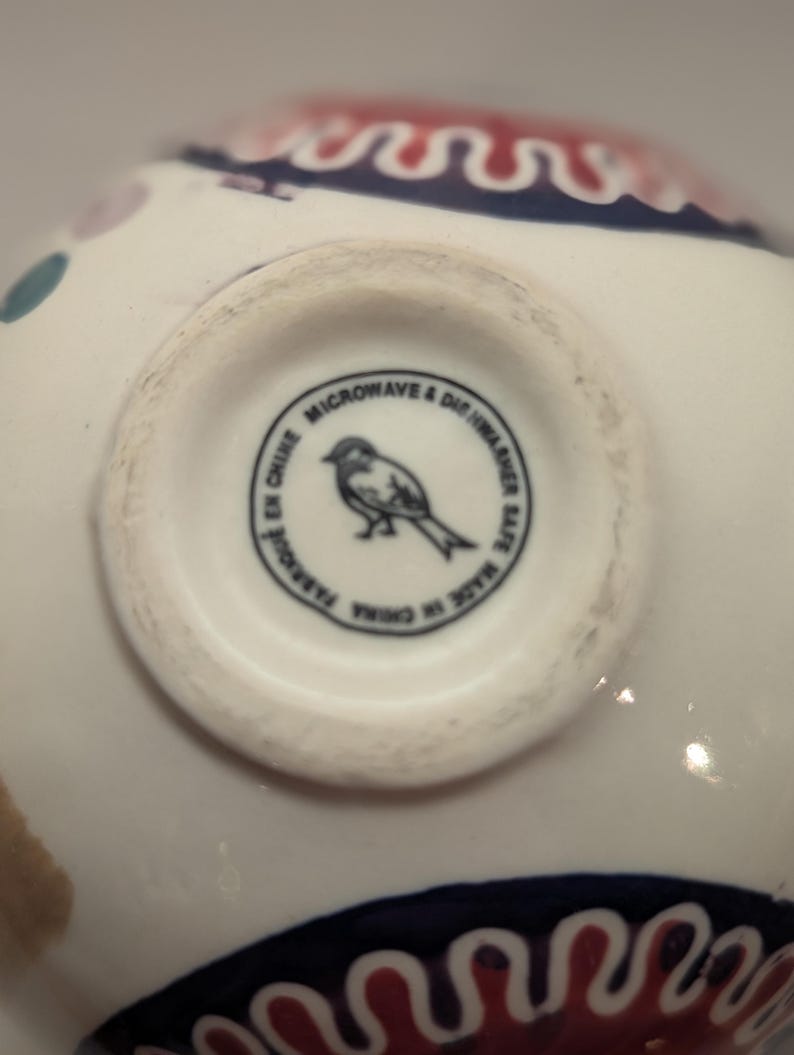 May include: The bottom of a white ceramic bowl with a black and white bird illustration and the text "Microwave & Dishwasher Safe. Made in China.  Parsol in China."