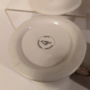 Pu&ograve; includere: Tazza in ceramica bianca con un design di uccello nero e il testo "Hand Wash" e "Made in China" sul fondo.